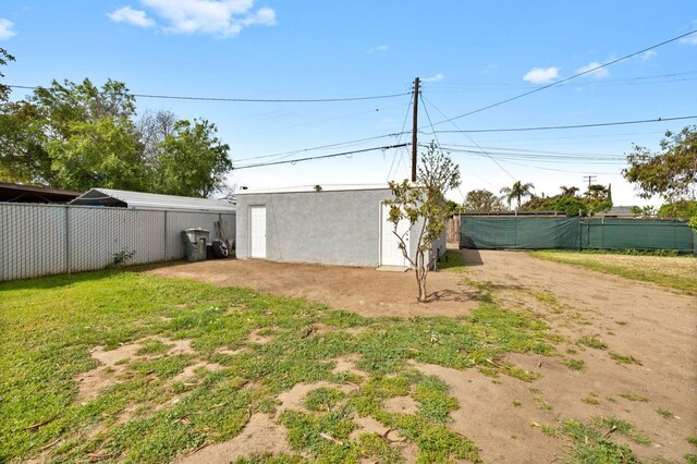 view of yard featuring driveway, an outbuilding, and fence
