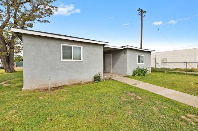view of front of house featuring a front lawn, stucco siding, and fence