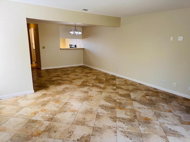 spare room featuring a chandelier and baseboards