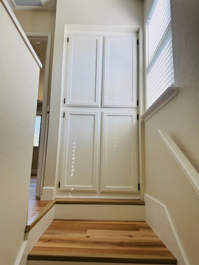stairway featuring a textured wall and wood finished floors
