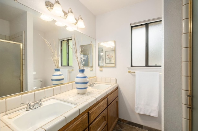 full bath with a sink, toilet, double vanity, and a stall shower