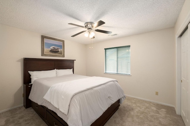 carpeted bedroom with baseboards, a closet, a textured ceiling, a ceiling fan, and visible vents