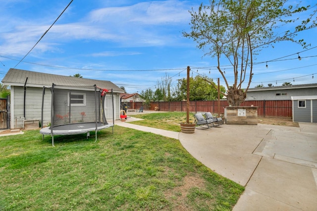 view of yard featuring a fenced backyard, an outdoor structure, a patio area, and a trampoline