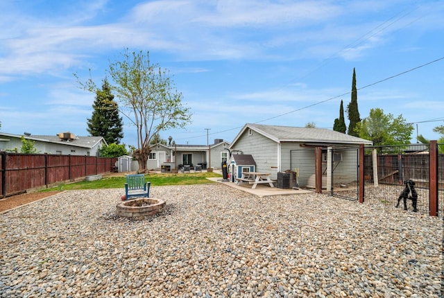 back of property with an outbuilding, an outdoor fire pit, a fenced backyard, and a patio area