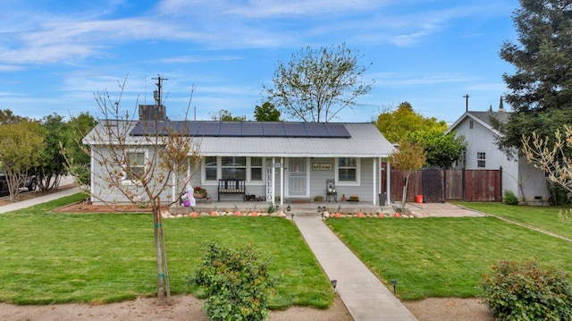 view of front of house with fence, a chimney, a front yard, solar panels, and a porch