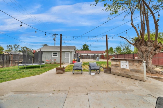view of patio with a trampoline, an outdoor structure, and a fenced backyard