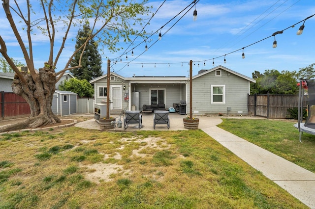 back of house with an outbuilding, a patio, a fenced backyard, a storage unit, and a trampoline