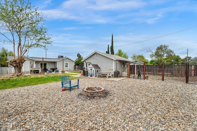 rear view of property featuring a patio, an outdoor fire pit, a fenced backyard, an outbuilding, and a yard