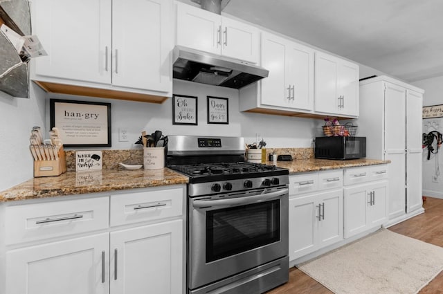 kitchen with light wood-style flooring, stainless steel range with gas cooktop, under cabinet range hood, white cabinetry, and black microwave