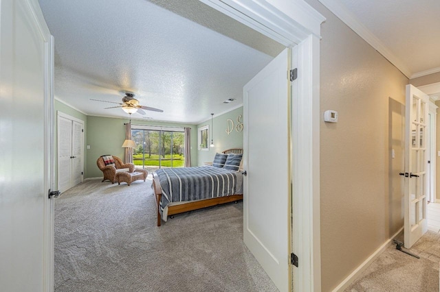 carpeted bedroom featuring a ceiling fan, ornamental molding, baseboards, and a textured ceiling
