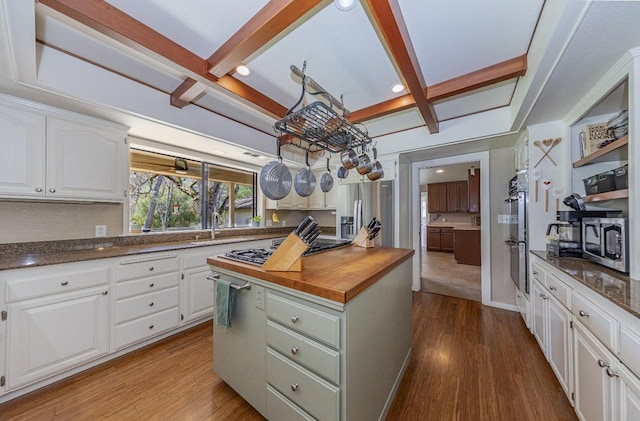 kitchen with white cabinets, appliances with stainless steel finishes, dark wood finished floors, beamed ceiling, and wood counters