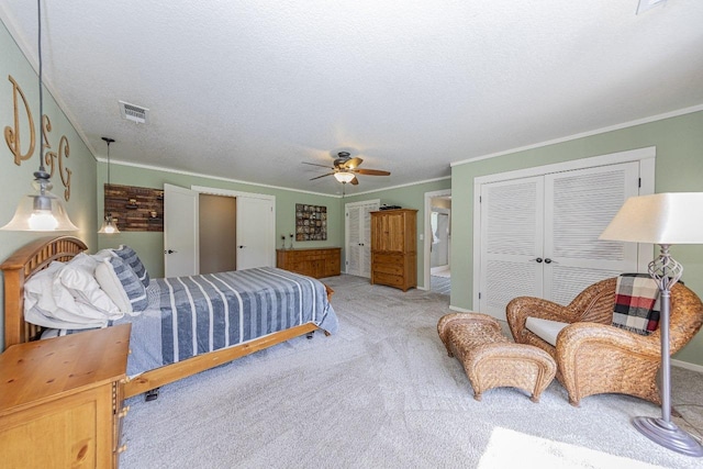 carpeted bedroom featuring ornamental molding, a textured ceiling, a closet, and visible vents