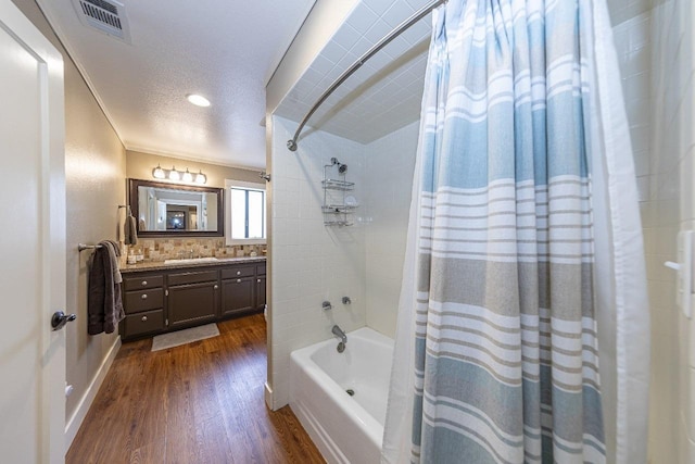 bathroom with vanity, a textured ceiling, visible vents, shower / bath combo, and wood finished floors