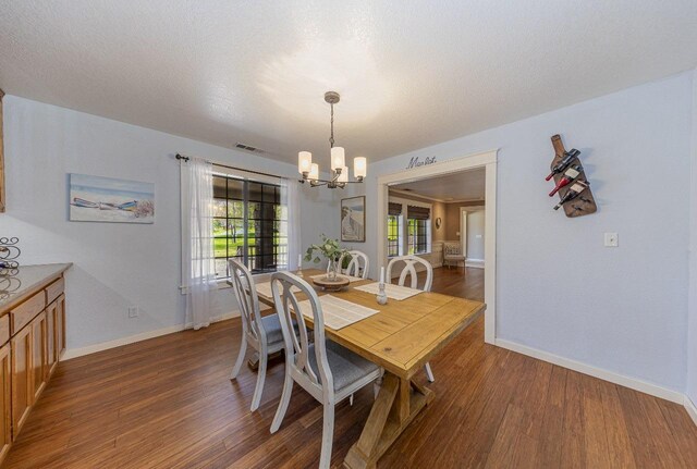 dining space with visible vents, a textured ceiling, wood finished floors, and a chandelier