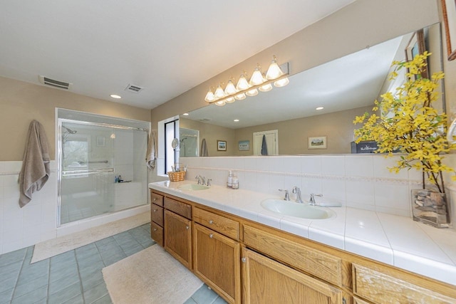 full bath with visible vents, a sink, a stall shower, and double vanity