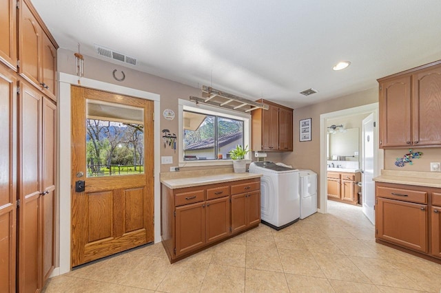 laundry room with light tile patterned floors, independent washer and dryer, cabinet space, and visible vents