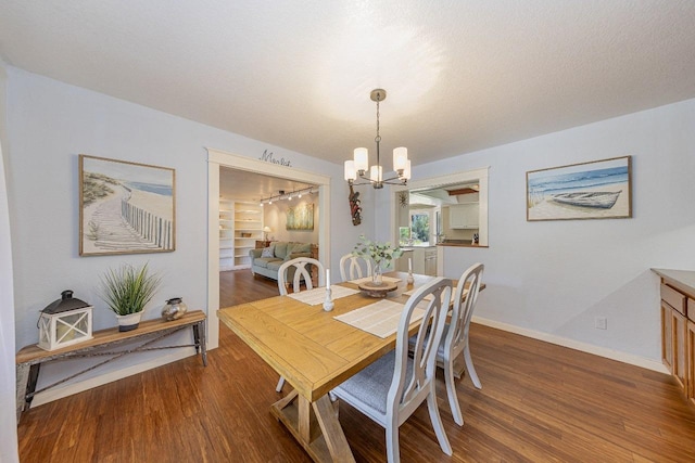dining room featuring baseboards, wood finished floors, and an inviting chandelier