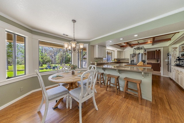 dining area featuring baseboards, visible vents, wood finished floors, and a notable chandelier