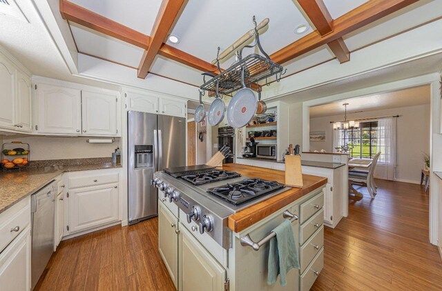 kitchen featuring coffered ceiling, a chandelier, light wood-style floors, and stainless steel appliances