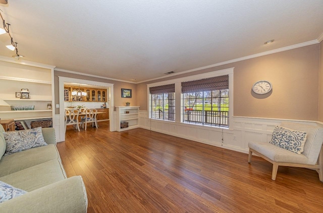 living room featuring visible vents, wainscoting, crown molding, and wood finished floors