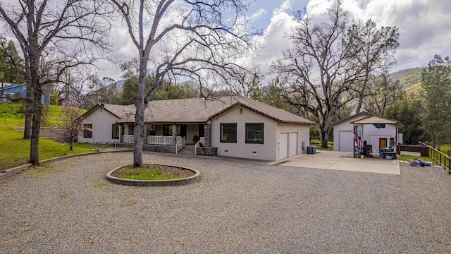 view of front facade with an outdoor structure, a porch, stucco siding, and a detached garage