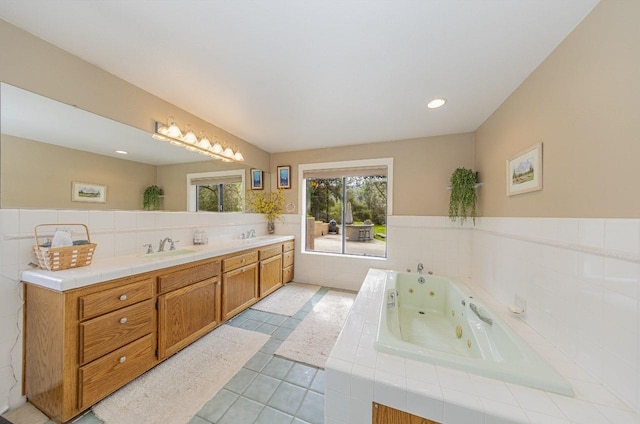 bathroom featuring tile patterned flooring, tile walls, a tub with jets, a sink, and double vanity
