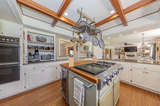 kitchen with dobule oven black, stainless steel microwave, coffered ceiling, and light wood-type flooring