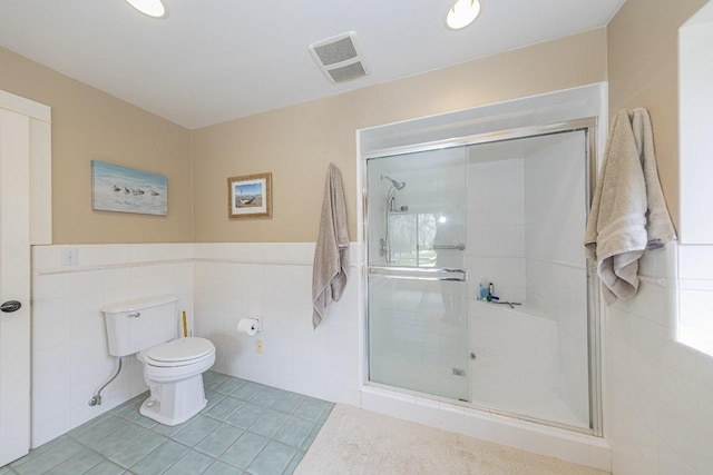 full bath with toilet, a shower stall, tile walls, and visible vents