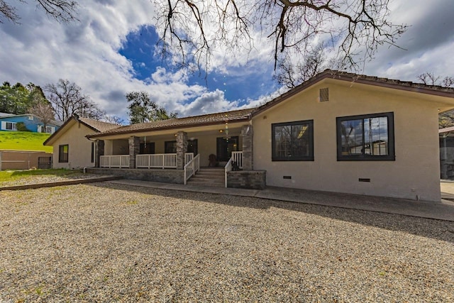 back of house featuring stucco siding, covered porch, and crawl space