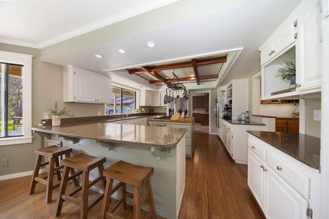 kitchen featuring white cabinetry, baseboards, dark stone counters, dark wood-style floors, and a peninsula