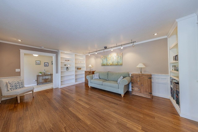 living room with wood finished floors, ornamental molding, and built in shelves