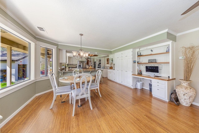 dining area with visible vents, ornamental molding, light wood-style flooring, and an inviting chandelier