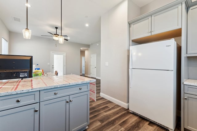 kitchen featuring visible vents, a ceiling fan, freestanding refrigerator, dark wood finished floors, and gray cabinetry