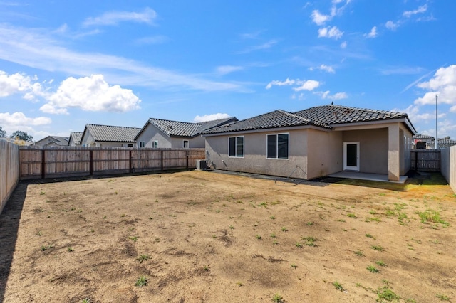 rear view of property with stucco siding, a patio area, a fenced backyard, central AC, and a tiled roof
