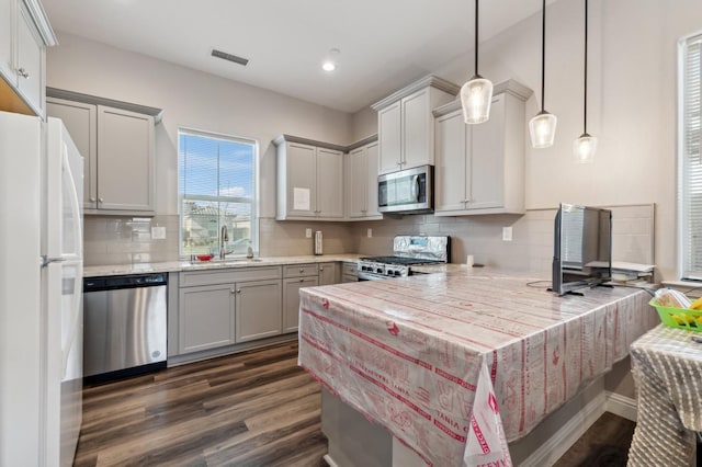 kitchen with dark wood finished floors, a peninsula, visible vents, light countertops, and stainless steel appliances