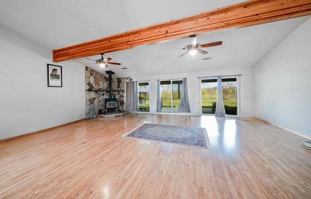 unfurnished living room featuring a wood stove, lofted ceiling with beams, visible vents, ceiling fan, and wood finished floors
