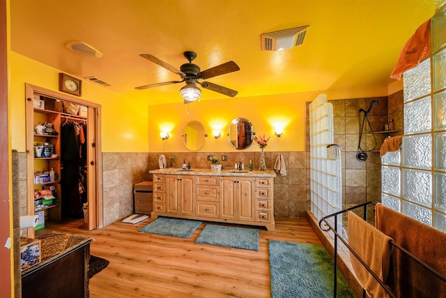 full bathroom with tile walls, visible vents, and a sink
