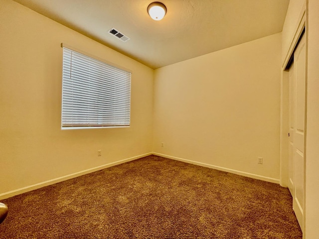 spare room with baseboards, visible vents, and dark carpet