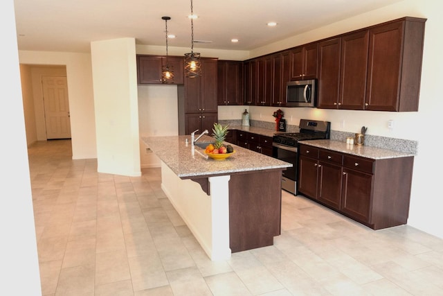 kitchen with recessed lighting, an island with sink, light stone counters, pendant lighting, and appliances with stainless steel finishes