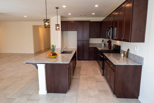 kitchen with a sink, light stone countertops, stainless steel microwave, gas range, and recessed lighting