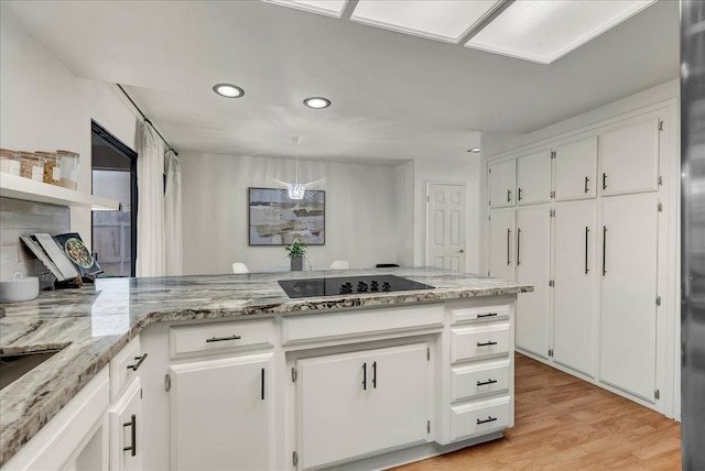 kitchen featuring light stone counters, black electric stovetop, light wood-style flooring, white cabinets, and recessed lighting