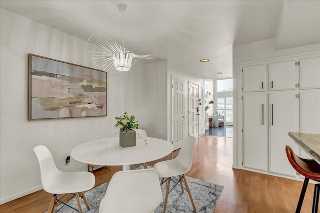 dining area featuring baseboards, a notable chandelier, and light wood-style floors