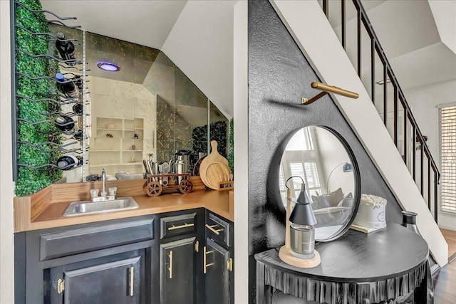bar with wood finished floors, stairs, indoor wet bar, and a sink