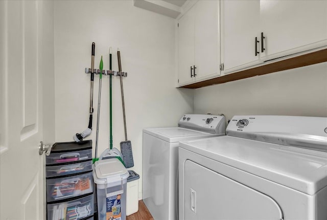 laundry room with separate washer and dryer, cabinet space, and wood finished floors