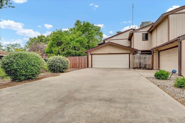 exterior space featuring a garage, concrete driveway, and fence