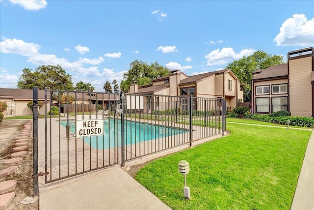 view of swimming pool featuring a lawn, fence, and a fenced in pool
