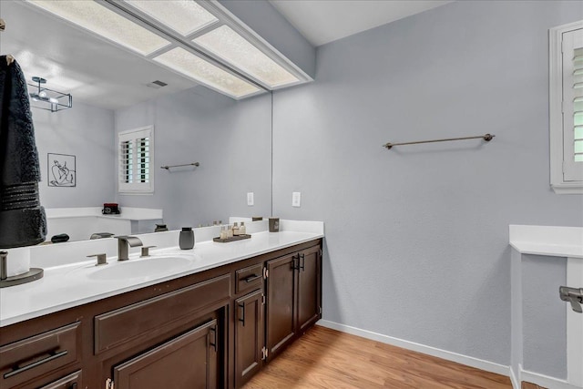 bathroom with baseboards, vanity, wood finished floors, and visible vents
