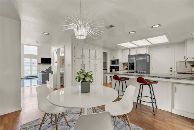dining room with an inviting chandelier, visible vents, recessed lighting, and light wood-style floors