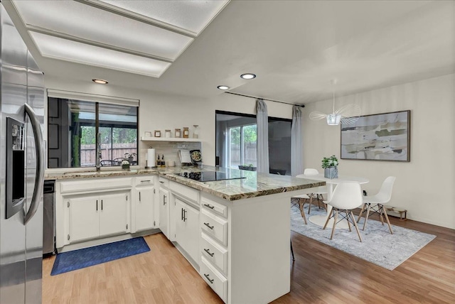 kitchen featuring white cabinets, a healthy amount of sunlight, stainless steel appliances, and light wood-style floors