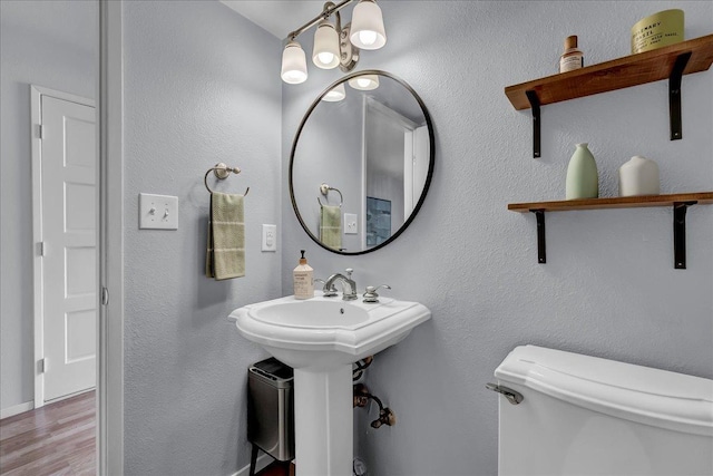 bathroom with toilet, wood finished floors, and a sink